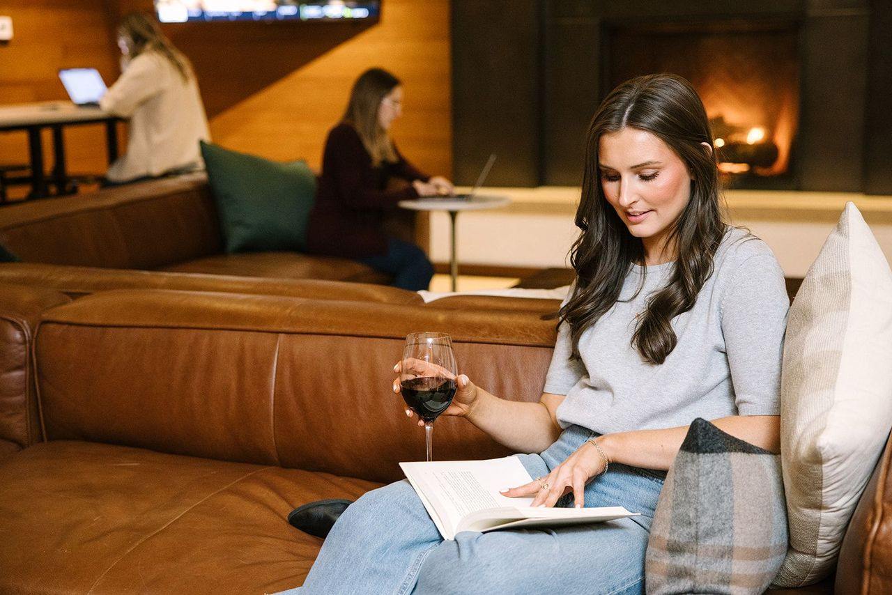 Woman reading a book while having wine